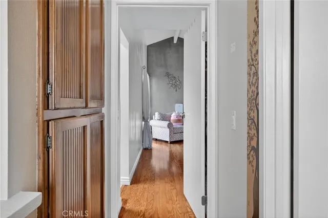a view of a hallway with wooden floor and a bathroom