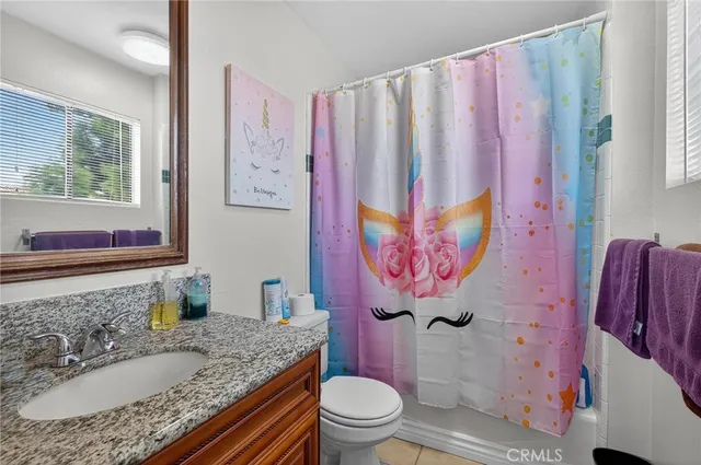 a bathroom with a granite countertop sink a toilet and a shower curtain