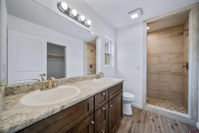 a bathroom with a granite countertop sink a toilet a mirror and shower