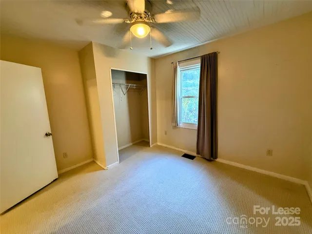 an empty room with a window and a ceiling fan