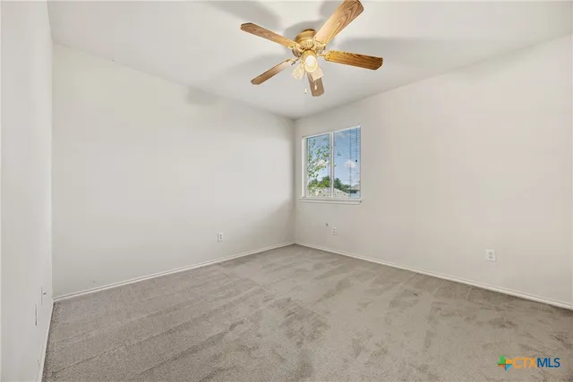 an empty room with a window and a ceiling fan