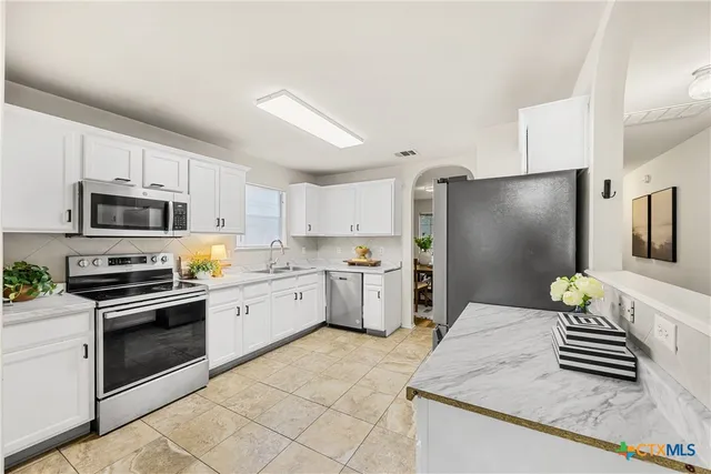 a kitchen with a sink stainless steel appliances and white cabinets