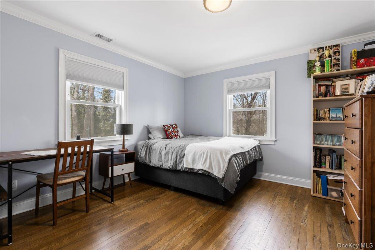 111 Spier Road Scarsdale, NY 10583 - Photo 23 of 37 a bed sitting in a bedroom next to a window with a book shelf and a wooden floor