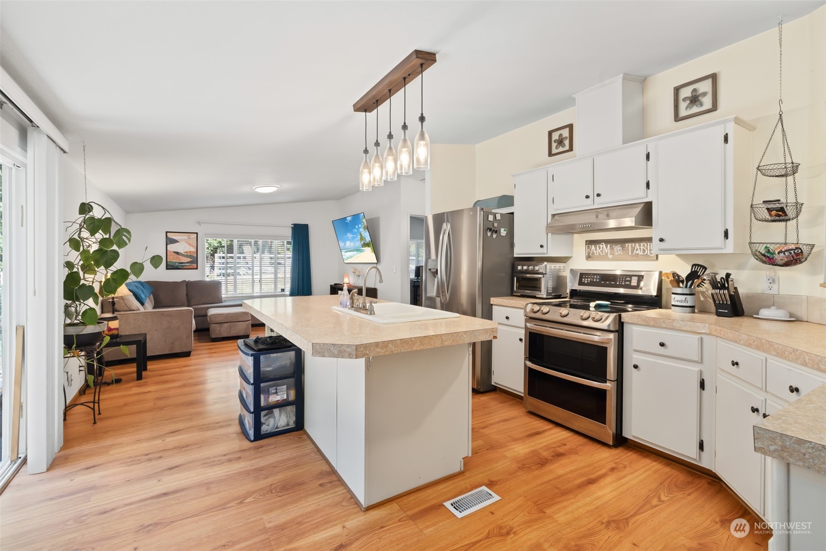4982 Happy Valley Road Sequim, WA 98382 - Photo 8 of 40 a kitchen with stainless steel appliances kitchen island granite countertop a stove a sink dishwasher and a refrigerator with wooden floor