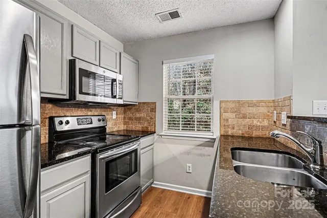 a kitchen with granite countertop a sink stainless steel appliances and cabinets