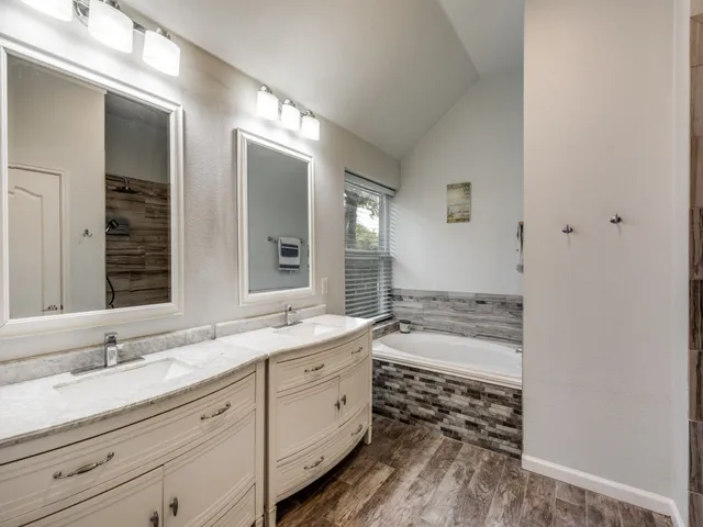 a spacious bathroom with a granite countertop sink mirror and bathtub