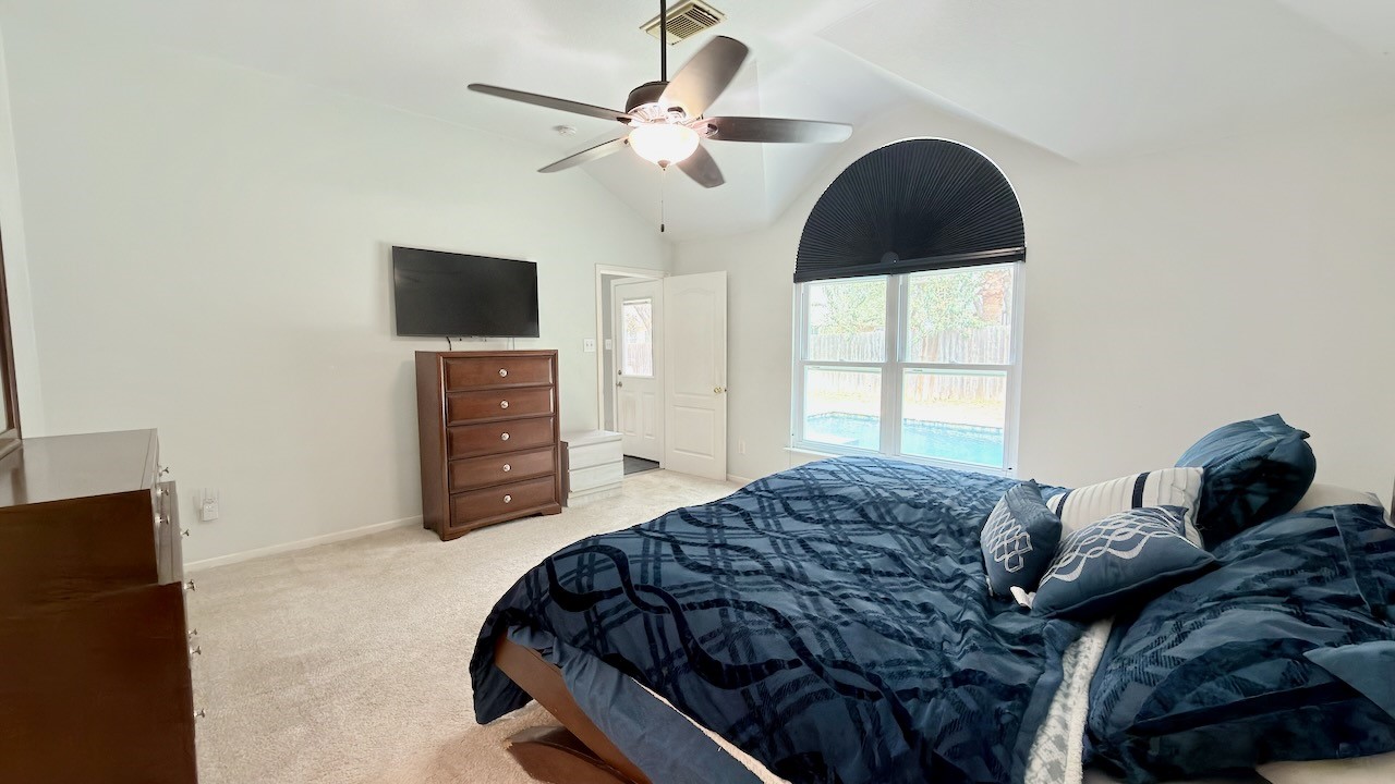 1902 Overland Drive Leander, TX 78641 - Photo 15 of 29 Tucked quietly at the back of the home, the primary suite offers a true sense of separation from the guest bedrooms, creating a peaceful and private retreat. Oversized windows frame calming views of the backyard, bringing in natural light while keeping the space connected to the outdoors. A generous walk-in closet adds everyday functionality, and custom blackout shades in the bedroom provide ideal light control for restful mornings and relaxed evenings.