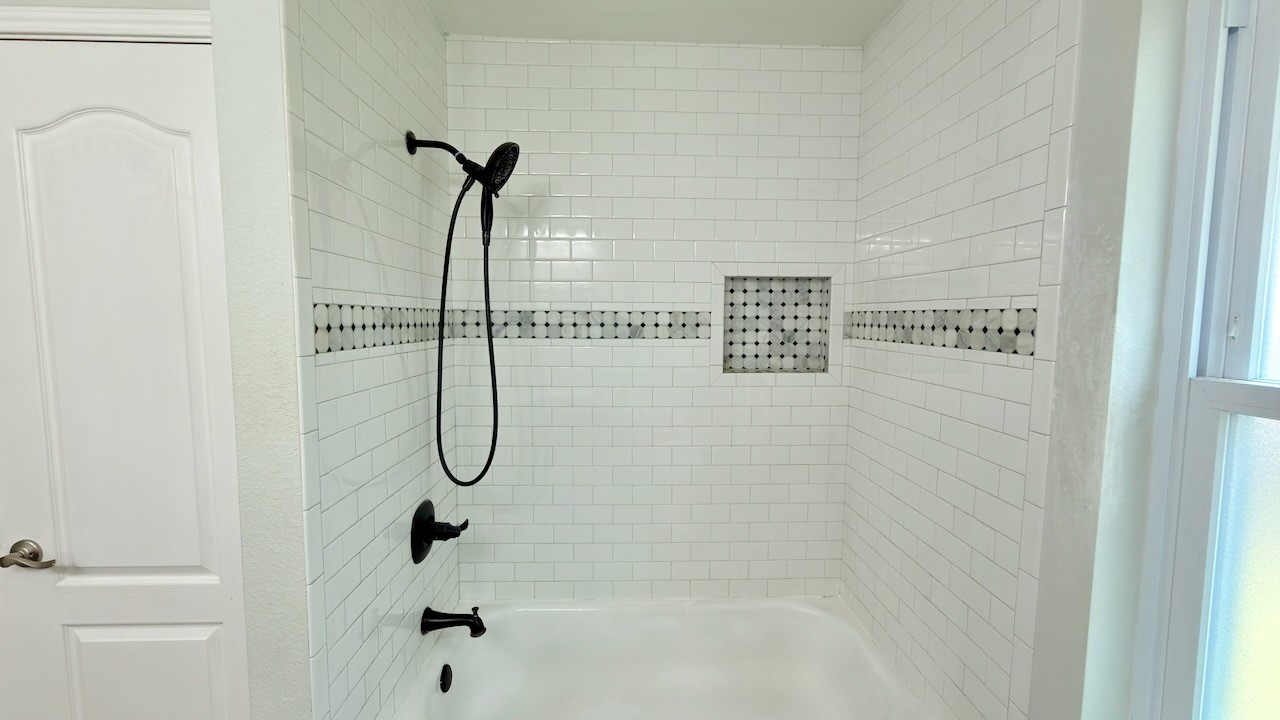 1902 Overland Drive Leander, TX 78641 - Photo 21 of 29 Thoughtfully updated, this secondary bathroom offers a clean, modern feel with tile flooring and a beautifully tiled shower that adds both style and durability. Double vanities provide everyday convenience, while a large linen closet keeps storage practical and organized. A window brings in natural light, creating a bright, comfortable space that feels fresh and well cared for.