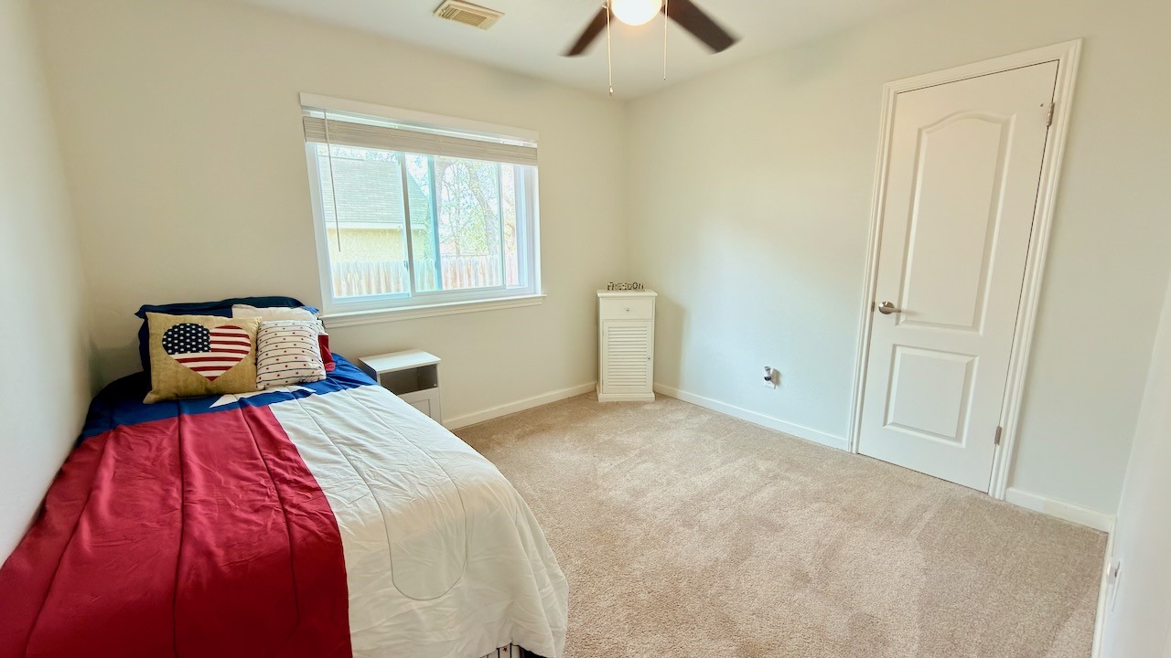 1902 Overland Drive Leander, TX 78641 - Photo 24 of 29 Secondary bedroom (2nd of 3 secondary bedrooms) filled with natural light, thanks to generous windows that keep the space bright and inviting throughout the day. A spacious walk-in closet offers excellent storage and flexibility, making this room ideal for guests or a personal retreat that adapts easily to your needs.