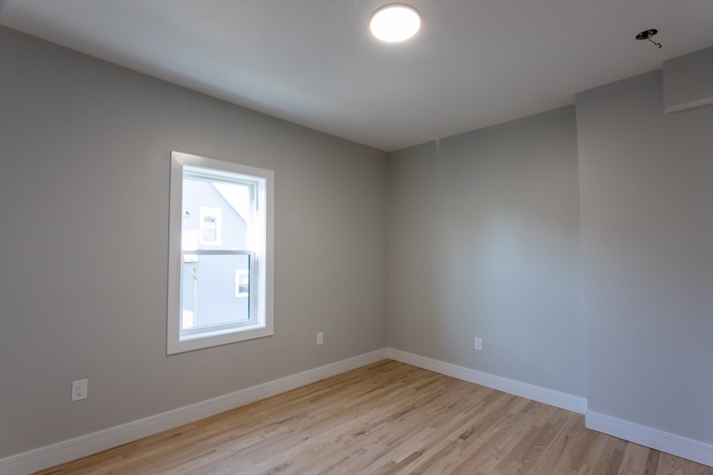 75 Sycamore Street Everett, MA 02149 - Photo 13 of 25 an empty room with wooden floor and windows