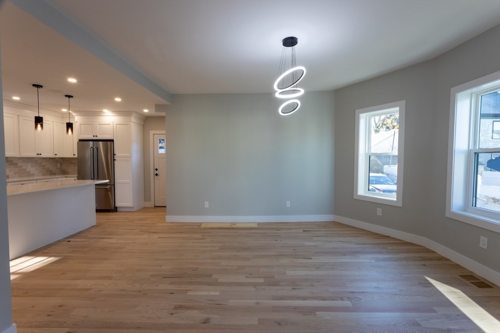 75 Sycamore Street Everett, MA 02149 - Photo 5 of 25 an empty room with wooden floor and windows