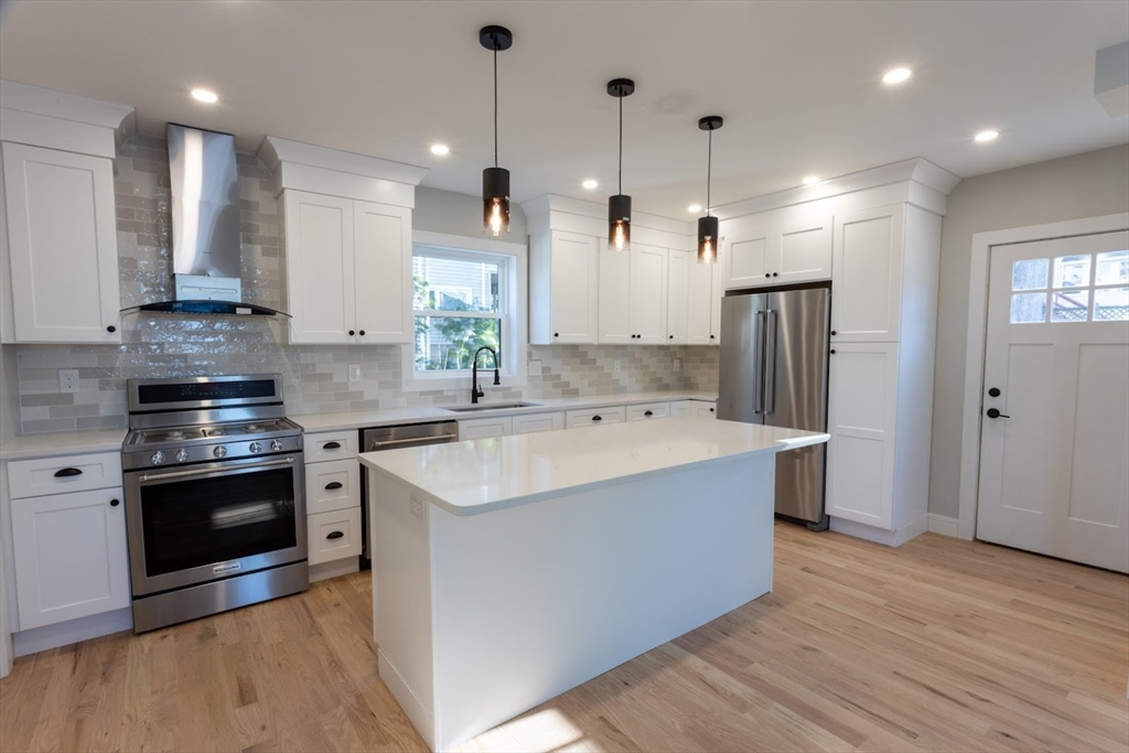 75 Sycamore Street Everett, MA 02149 - Photo 6 of 25 a kitchen with stainless steel appliances granite countertop a sink a stove a refrigerator and a oven with wooden floor
