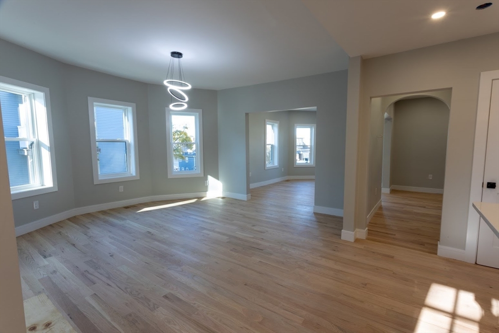 75 Sycamore Street Everett, MA 02149 - Photo 7 of 25 an empty room with wooden floor and windows