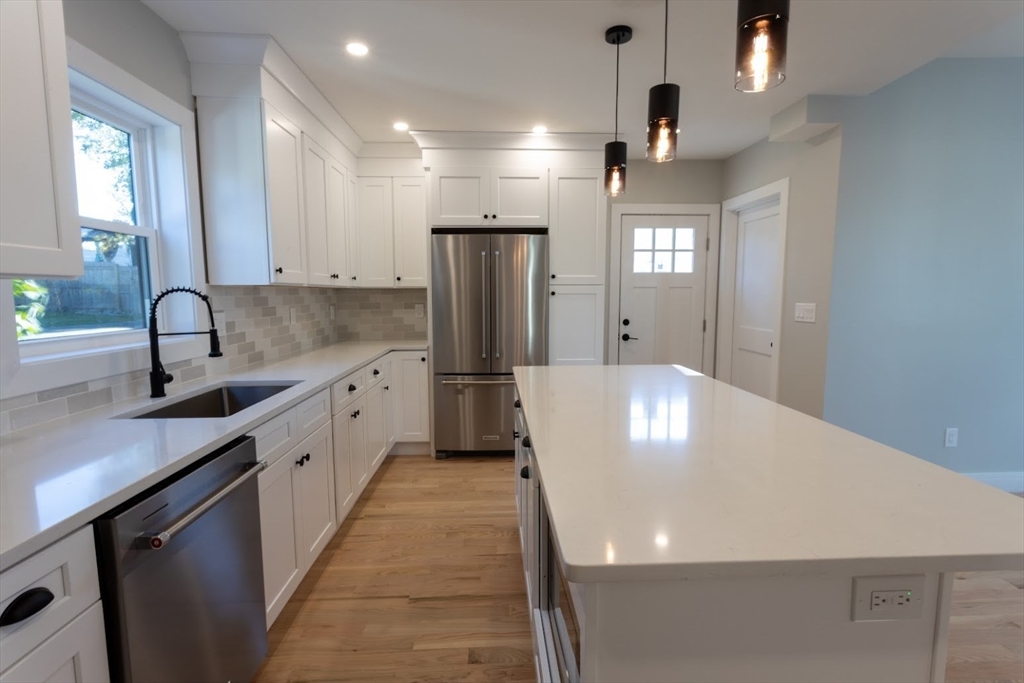 75 Sycamore Street Everett, MA 02149 - Photo 9 of 25 a large kitchen with stainless steel appliances a large counter top a sink a refrigerator and a window