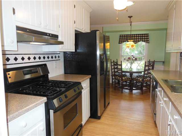 1115 Briardale Road Durham, NC 27712 - Photo 11 of 25 a kitchen with granite countertop a stove a refrigerator and a wooden cabinets