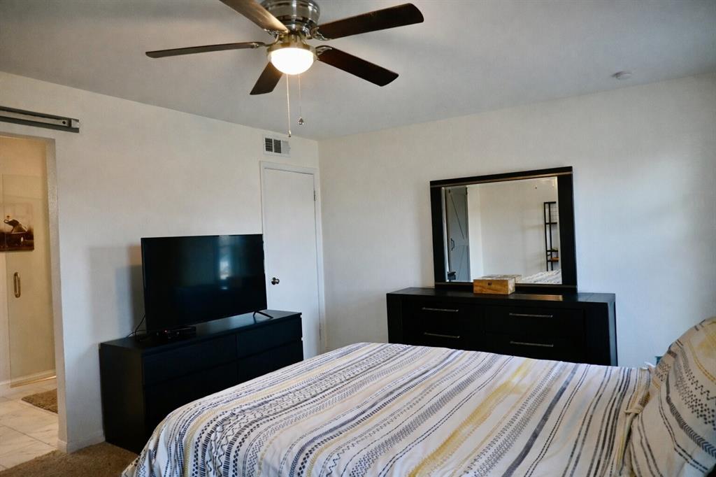 2223 Ridgedale Drive Carrollton, TX 75006 - Photo 10 of 27 a bedroom with a bed and a flat tv screen on dresser