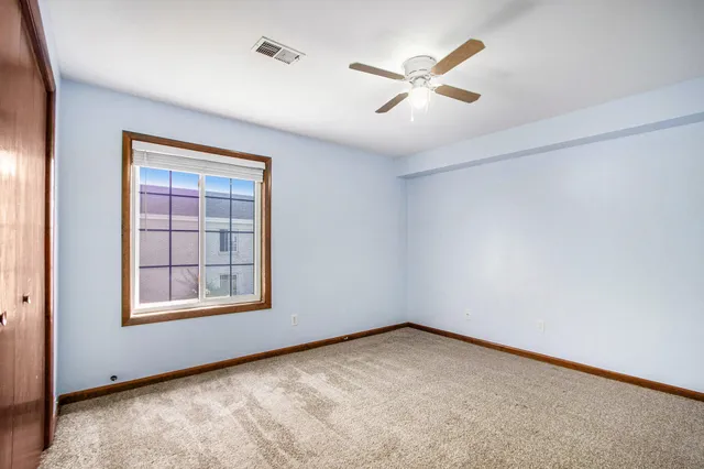 an empty room with ceiling fan and windows