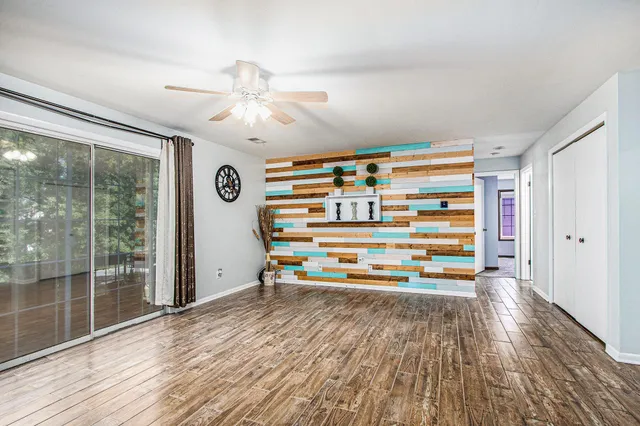a view of empty room with wooden floor and fan