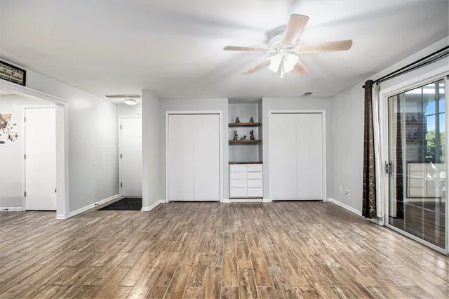 a view of empty room with wooden floor and fan