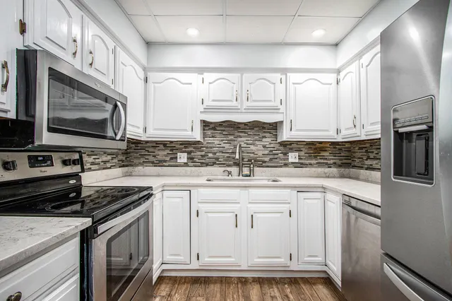 a kitchen with stainless steel appliances granite countertop a stove a sink and a microwave