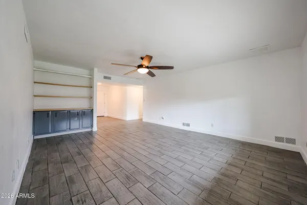 a view of empty room with wooden floor and fan