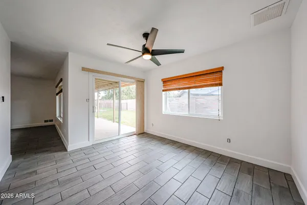 a view of empty room with wooden floor and fan