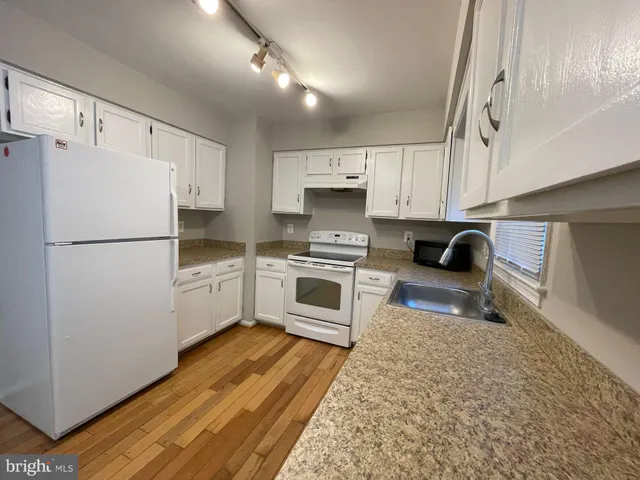 a kitchen with white cabinets and white appliances