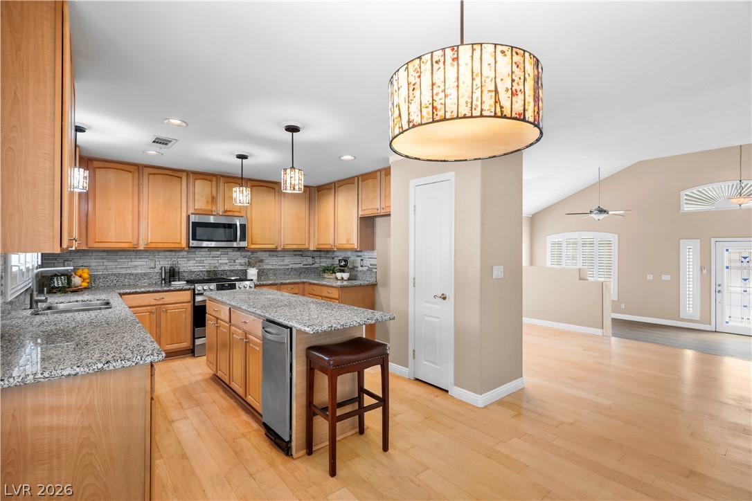 708 Vortex Avenue Henderson, NV 89002 - Photo 14 of 71 Chef-inspired kitchen boasts stainless steel appliances, granite countertops, and light wood flooring.
