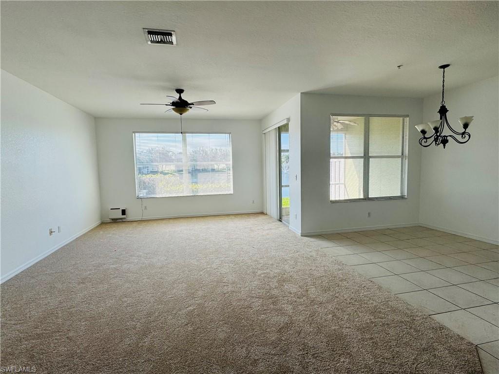1400 Mariposa Circle, Unit 103 Naples, FL 34105 - Photo 4 of 22 an empty room with windows and chandelier fan