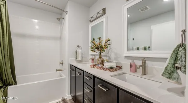 a bathroom with a sink a large mirror and a bath tub
