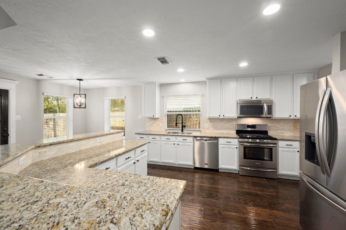 7 Delta Mill Court Conroe, TX 77385 - Photo 11 of 25 a large kitchen with cabinets wooden floor and stainless steel appliances