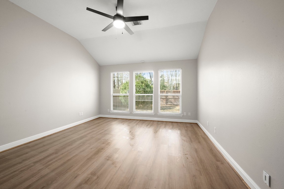 7 Delta Mill Court Conroe, TX 77385 - Photo 12 of 25 an empty room with wooden floor fan and windows