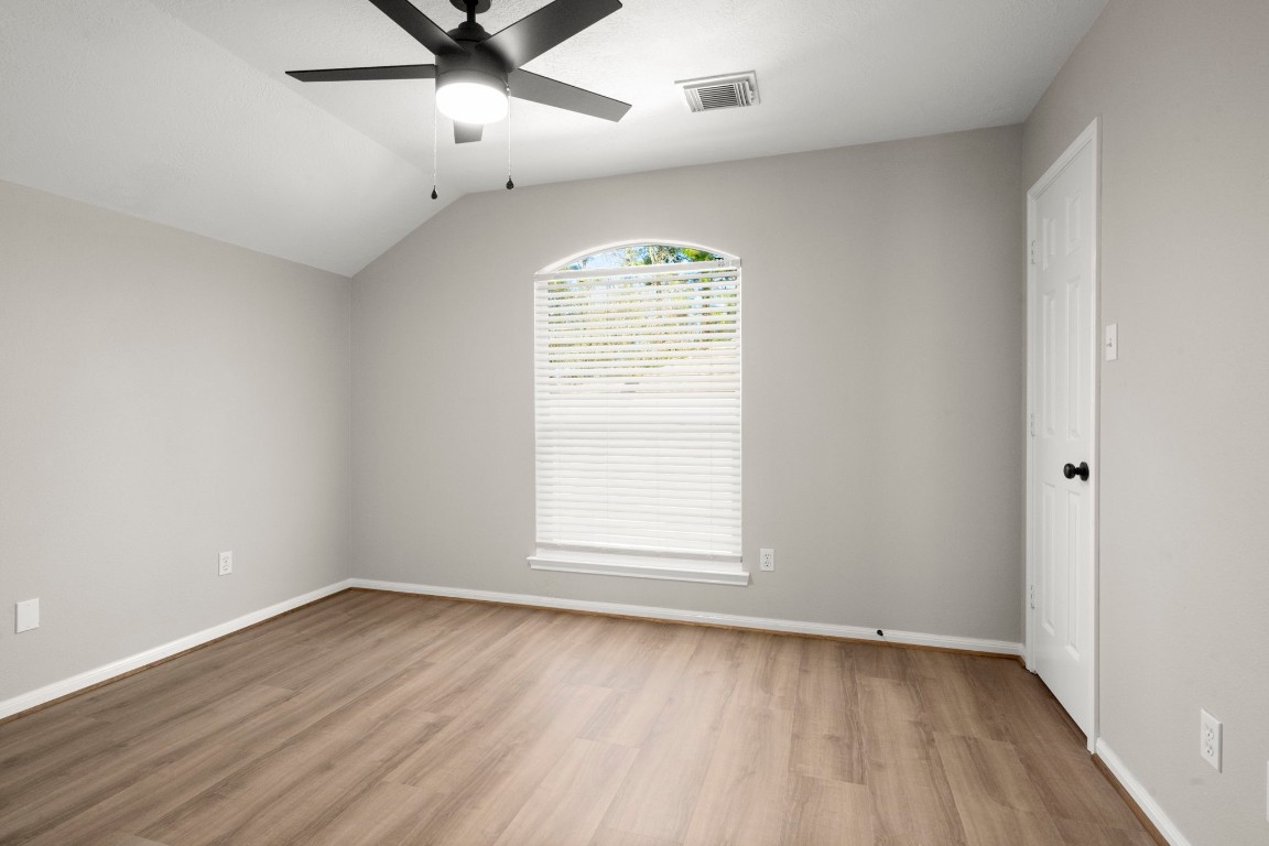 7 Delta Mill Court Conroe, TX 77385 - Photo 19 of 25 an empty room with wooden floor fan and windows