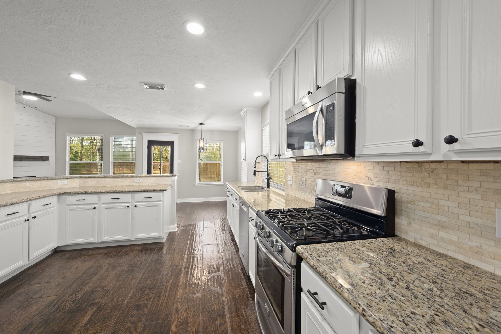 7 Delta Mill Court Conroe, TX 77385 - Photo 8 of 25 a kitchen with stainless steel appliances granite countertop a stove a sink and a microwave