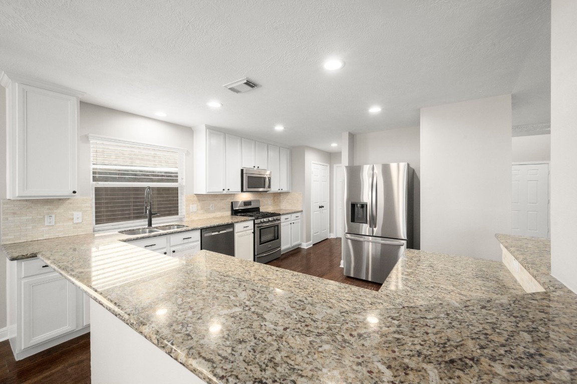 7 Delta Mill Court Conroe, TX 77385 - Photo 9 of 25 a kitchen with stainless steel appliances granite countertop a sink refrigerator and microwave