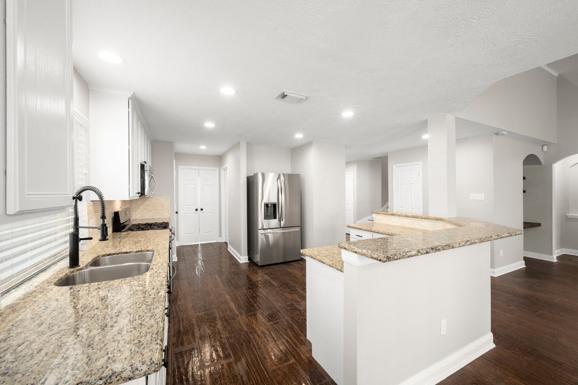 7 Delta Mill Court Conroe, TX 77385 - Photo 10 of 25 a large kitchen with stainless steel appliances kitchen island granite countertop a large island in the center