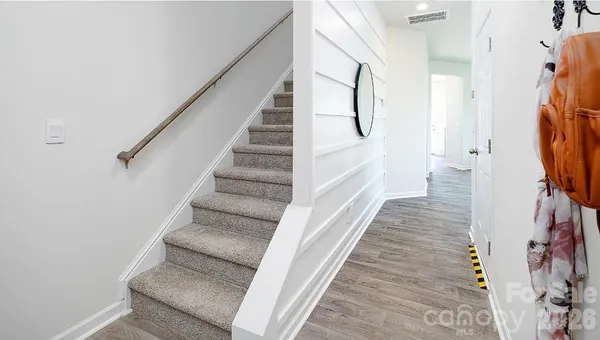 a view of staircase with white walls and a rug