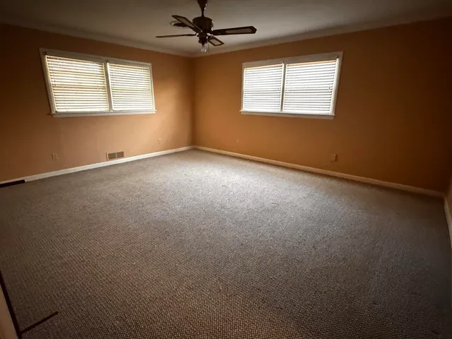 an empty room with a window and a fan
