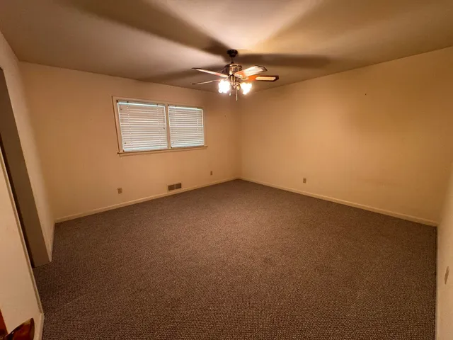 an empty room with a fan & a window