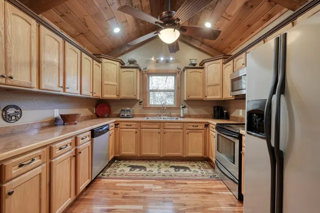 a kitchen with stainless steel appliances granite countertop a refrigerator a sink dishwasher a stove with white cabinets and wooden floor