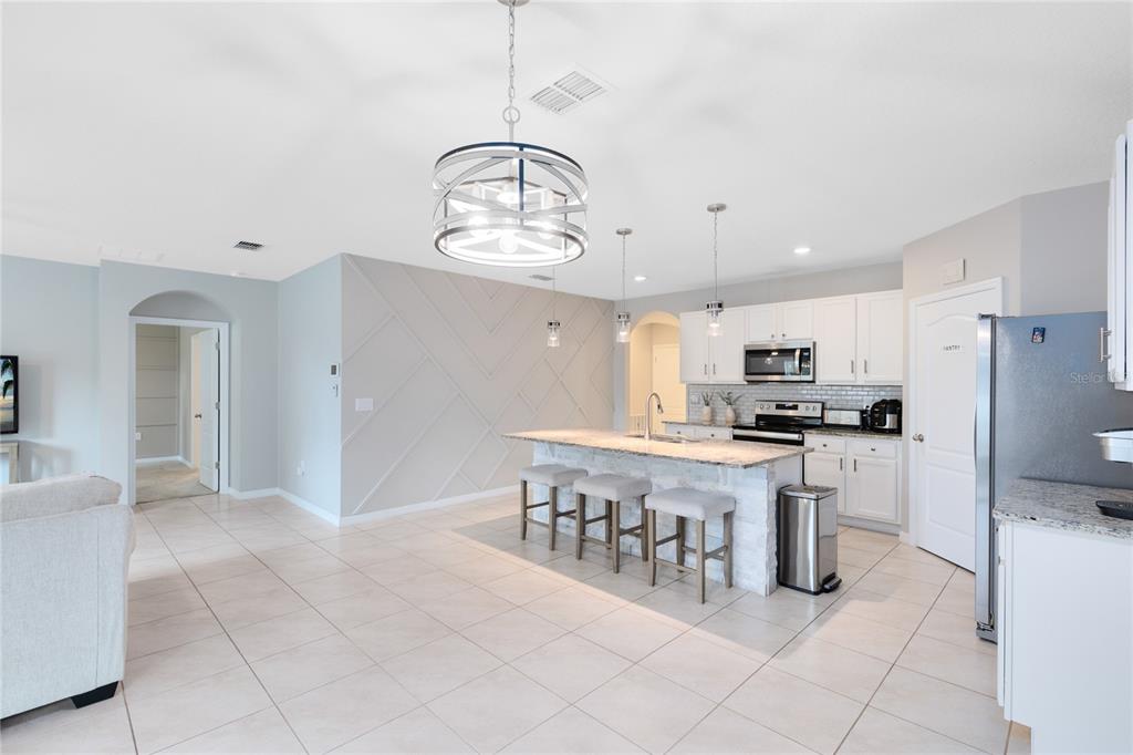 1600 Spray Terrace St. Cloud, FL 34771 - Photo 3 of 30 a kitchen with stainless steel appliances kitchen island granite countertop a refrigerator a stove a sink and a dining table with wooden floor