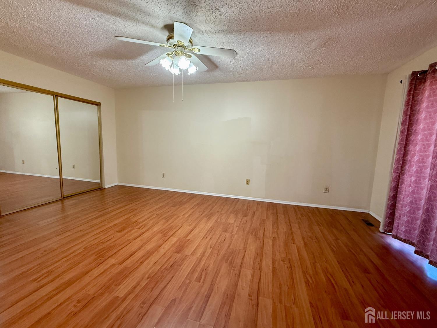 136 Westgate Drive Edison, NJ 08820 - Photo 11 of 17 an empty room with wooden floor and chandelier fan