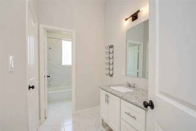 a bathroom with a granite countertop sink a mirror and a shower