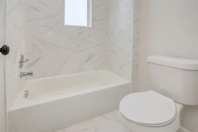 a white toilet sitting next to a bath tub