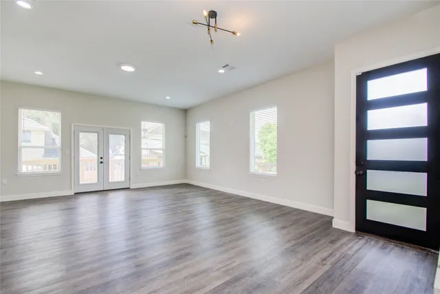 a view of an empty room with wooden floor and window