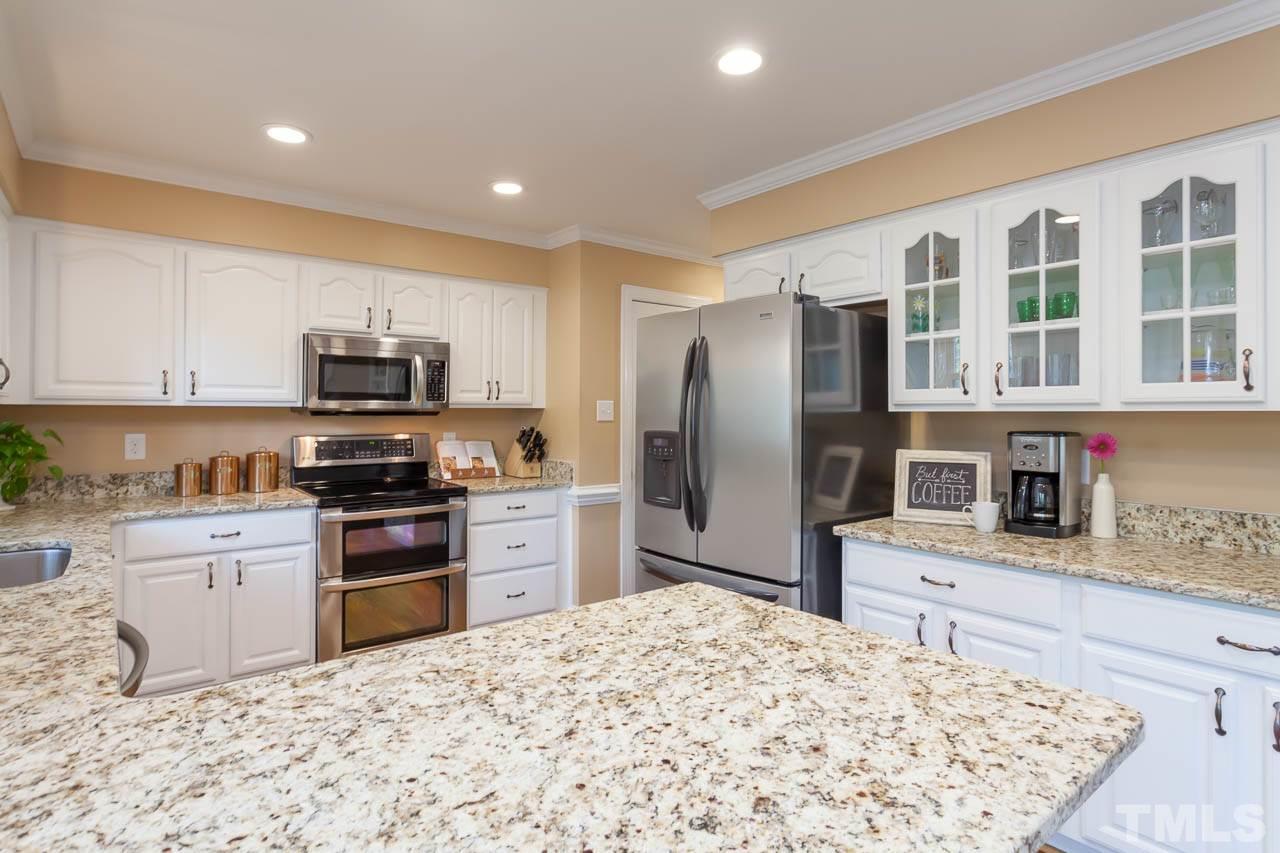 8805 Bickley Place Raleigh, NC 27613 - Photo 3 of 25 a kitchen with stainless steel appliances granite countertop a refrigerator sink stove microwave and cabinets