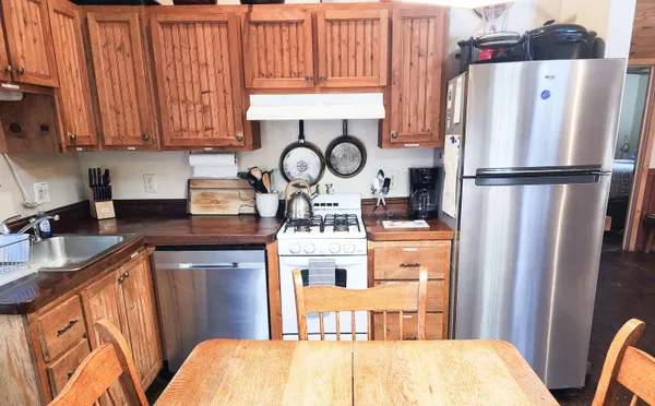 a kitchen with stainless steel appliances granite countertop a refrigerator a stove a sink dishwasher and white cabinets with wooden floor