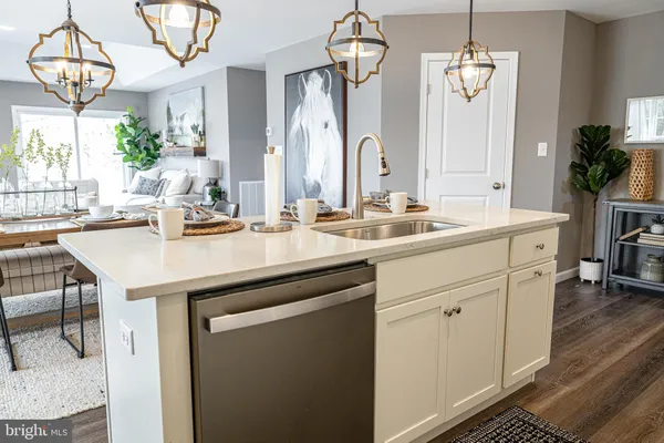 a kitchen with a sink dishwasher cabinets and dining table with wooden floor