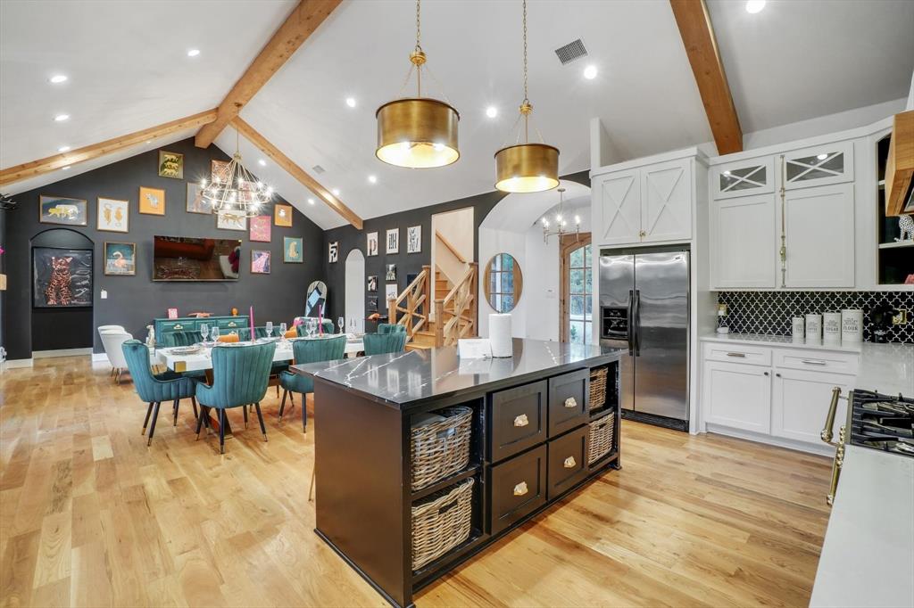 a kitchen with stainless steel appliances kitchen island granite countertop a table chairs in it and wooden floors