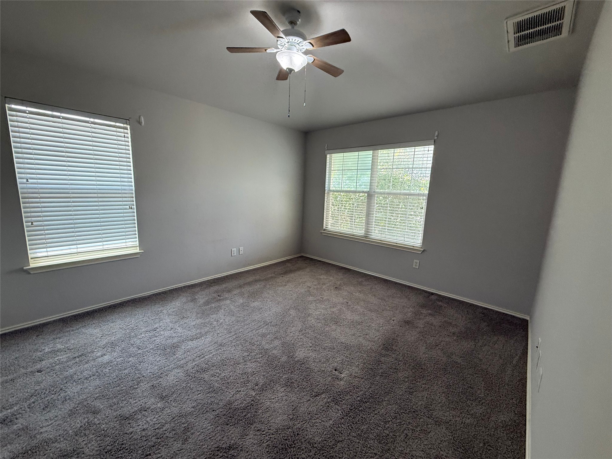 1900 Scofield Ridge Parkway, Unit 4701 Austin, TX 78727 - Photo 8 of 27 A spacious room offers ample natural light and plush carpet underfoot, creating a comfortable ambiance.